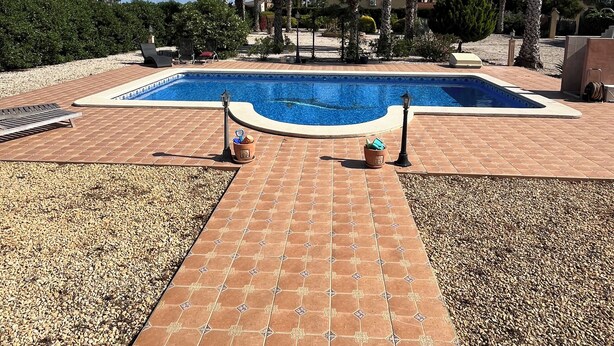 A swimming pool with a tiled deck, surrounded by palm trees and a clear blue sky. - Mediterranean villa with private pool 20 minutes from the beaches of La Marina (Catral)