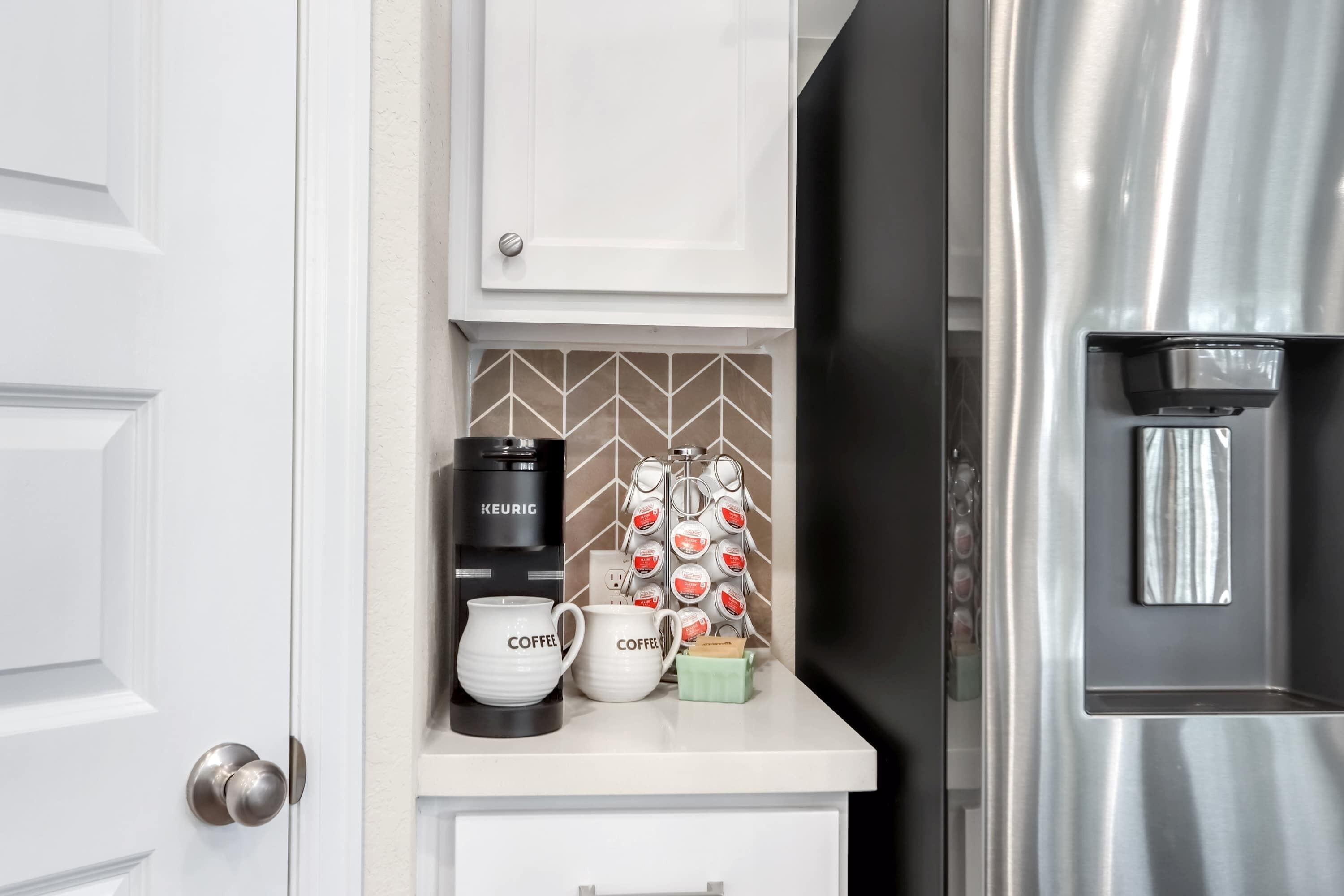 A kitchenette with a coffee maker, mugs, and a water dispenser.