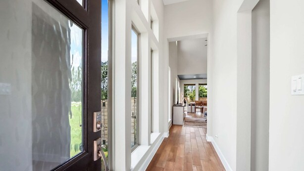 A modern hallway with wooden flooring, large windows, and a view of the outdoors. - Dakota Cottage - Stay for 10 (New Braunfels)
