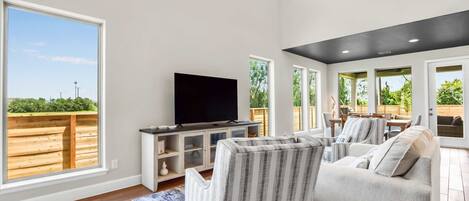 A spacious living room with a large TV, comfortable seating, and a view of the outdoors.