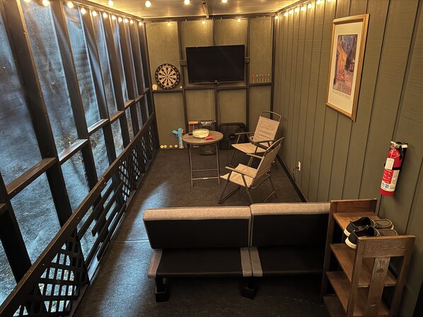 A cozy room with a sofa, a small table, and a TV. There are windows with curtains, a fire extinguisher, and a framed picture on the wall. - Sunset Hill. Rustic retreat just minutes from the town of New Market (New Market)