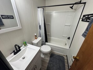 Ein kleines Badezimmer mit einem weißen Waschbecken, einer Toilette und einer Badewanne.