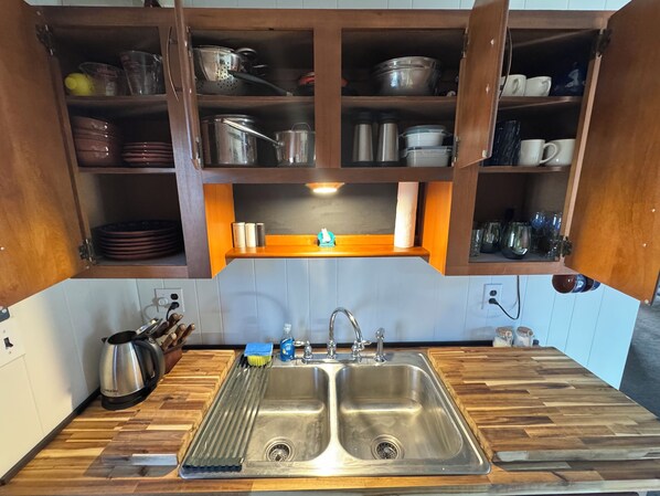 Een keuken met houten kastjes, een dubbele spoelbak en diverse keukengerei.