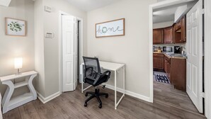 A home office with a desk and chair, a framed 'home' sign, a framed plant, and a thermostat on the wall. - Airport, Stadiums & City Life in ATL! (Atlanta)