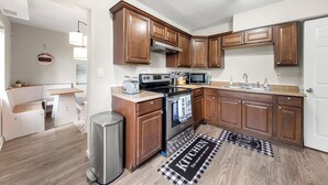 A compact kitchen with wooden cabinets, a stainless steel stove, and a microwave. - Airport, Stadiums & City Life in ATL! (Atlanta)