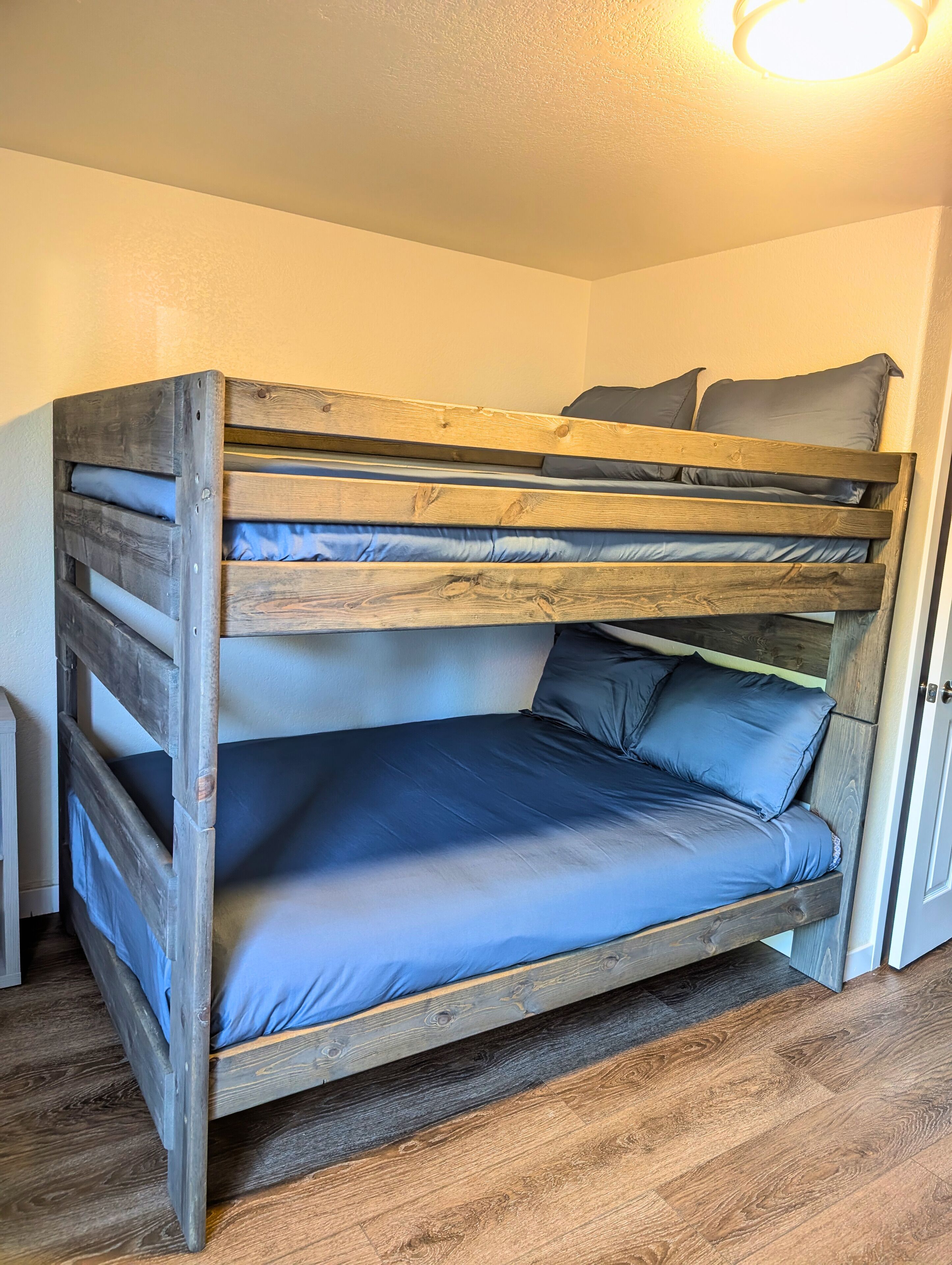 A bunk bed with a wooden frame and blue bedding.