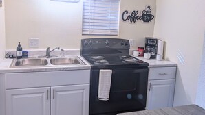 Una cocina compacta con estufa, lavamanos y una decoración de pared temática del café.
