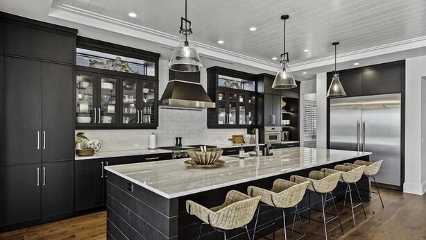 A modern kitchen with dark cabinetry, a large island, and bar stools.
