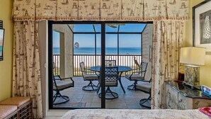 Une chambre dotée d’un balcon, avec une table et des chaises, un lit et des rideaux sur le thème de la marine.