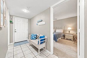 A bedroom with a bed, bedside table, lamp, and a door leading to another room. - Sea Oats 352 | 2BR/2BA Gulf-Front Luxury Retreat (Boca Grande)