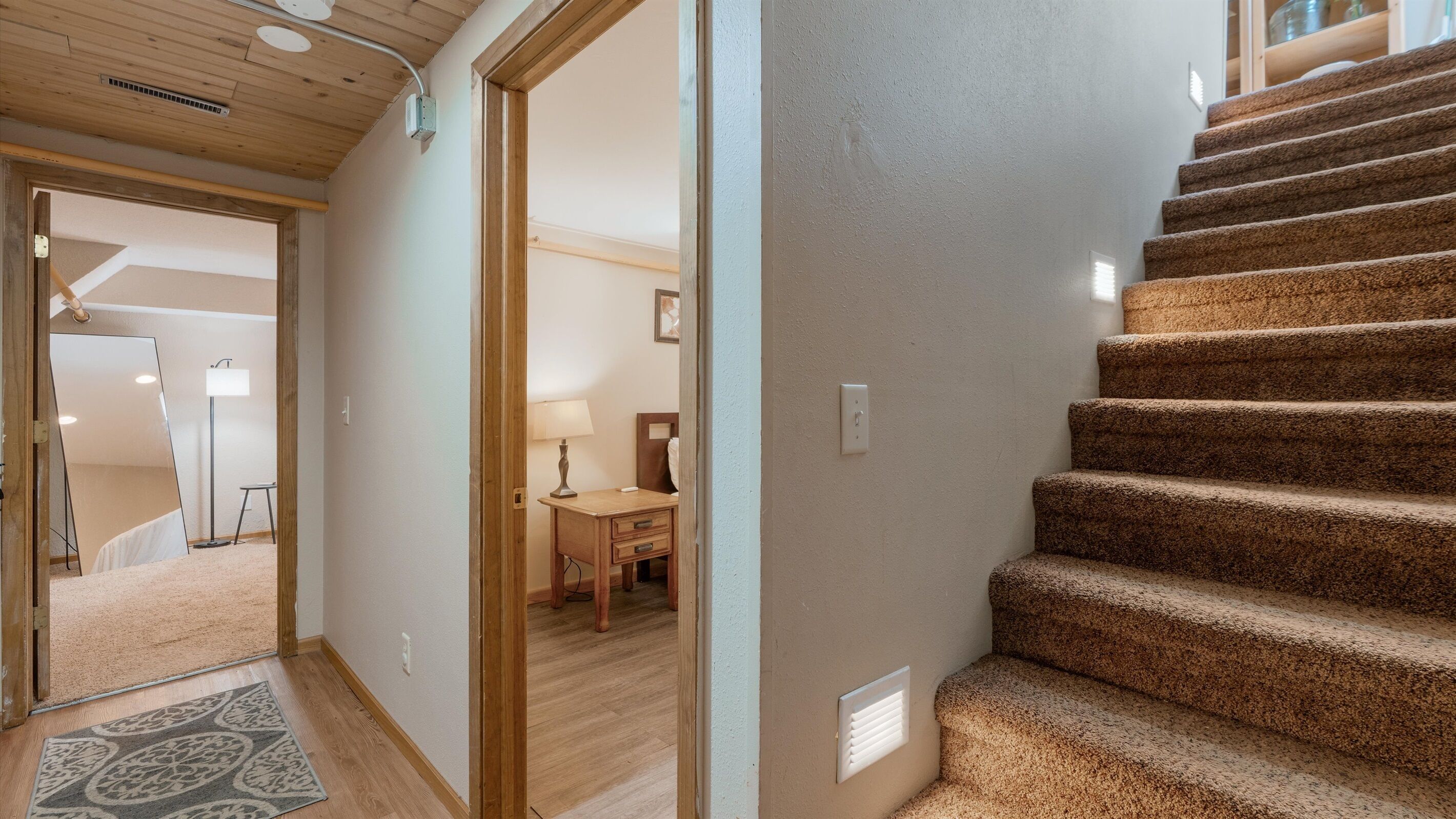 A staircase with carpeted steps leading to a bedroom.