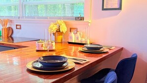 Een moderne keuken met een houten aanrecht, blauwe stoelen en een hangplant.