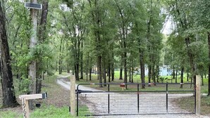 A gated entrance to a campground with a dirt path leading through a wooded area.