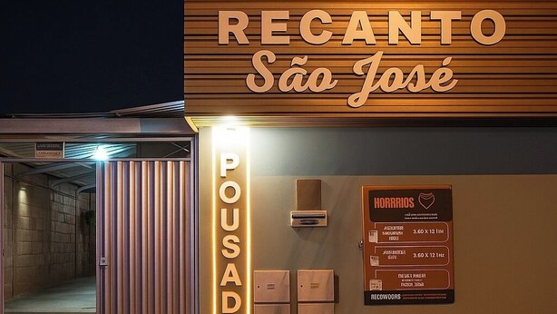 Entrada de hotel con un cartel que dice "RECANTO São José" y un cartel vertical que indica "POUSADA".
