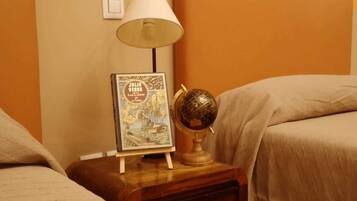 Una mesita de noche con una lámpara, un libro enmarcado y un globo terráqueo.