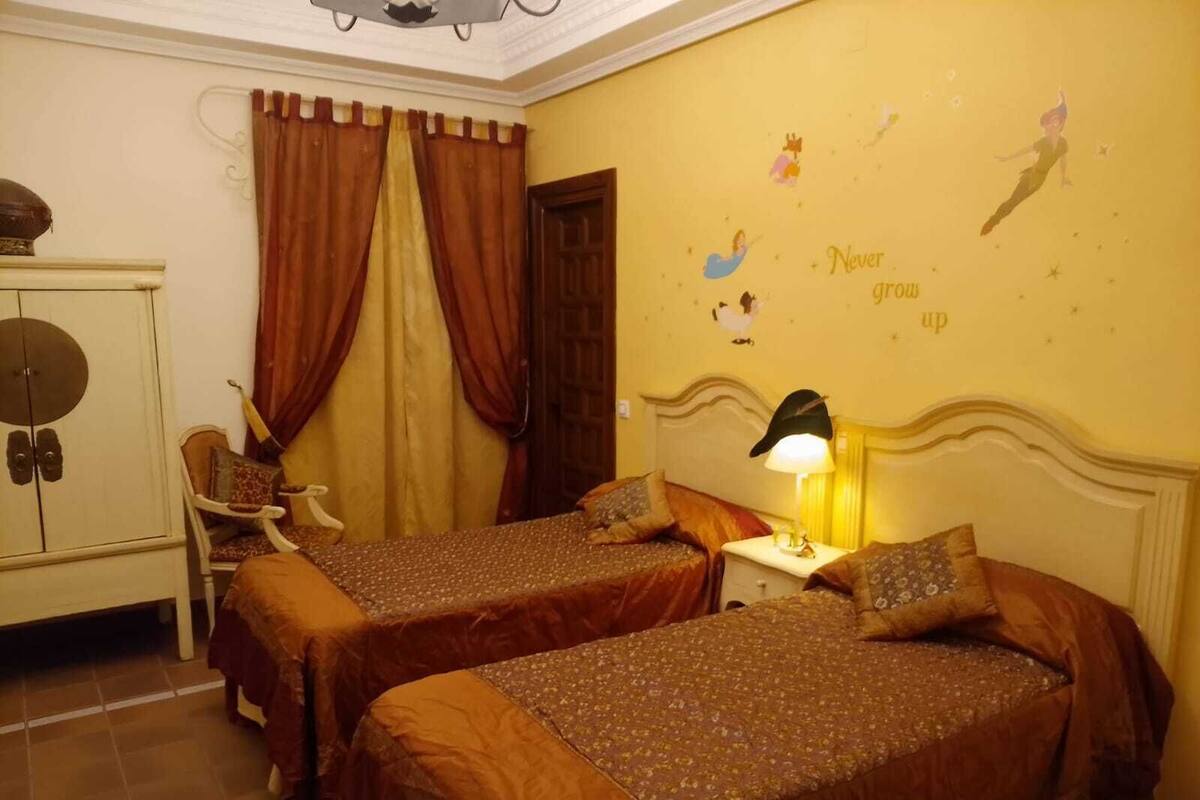 A hotel room with two beds, a wardrobe, a chair, and a wall with a motivational quote.