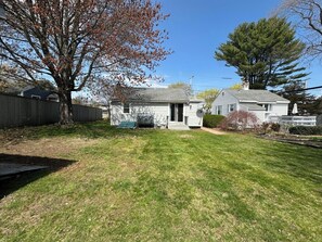 A residential property with a well-maintained lawn, a wooden fence, and two houses with a chimney. - Pet-friendly 2-Bedroom House in Ogunquit Steps from Foot Bridge Beach (Ogunquit)