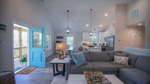 A spacious living room with a gray sectional sofa, a coffee table with decorative items, and a kitchen area in the background. - Carova Beach, 4x4, Wild Horses, New home built in 2025.
🏝 (Corolla)