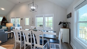 A spacious dining area with a high ceiling, white walls, and large windows offering a view of the outdoors. - Carova Beach, 4x4, Wild Horses, New home built in 2025.
🏝 (Corolla)