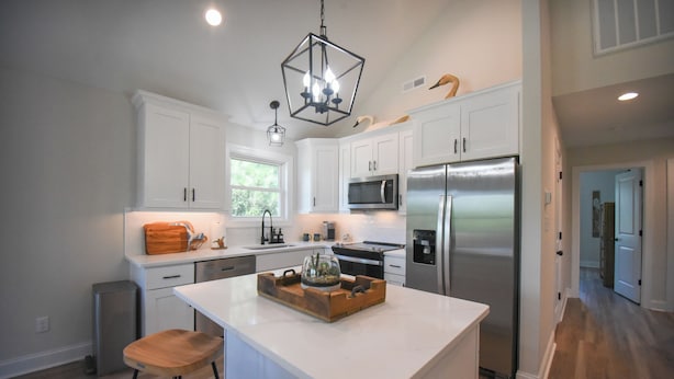 A modern kitchen with white cabinetry, a stainless steel refrigerator, a built-in oven, and a central island with stools. - Carova Beach, 4x4, Wild Horses, New home built in 2025.
🏝 (Corolla)