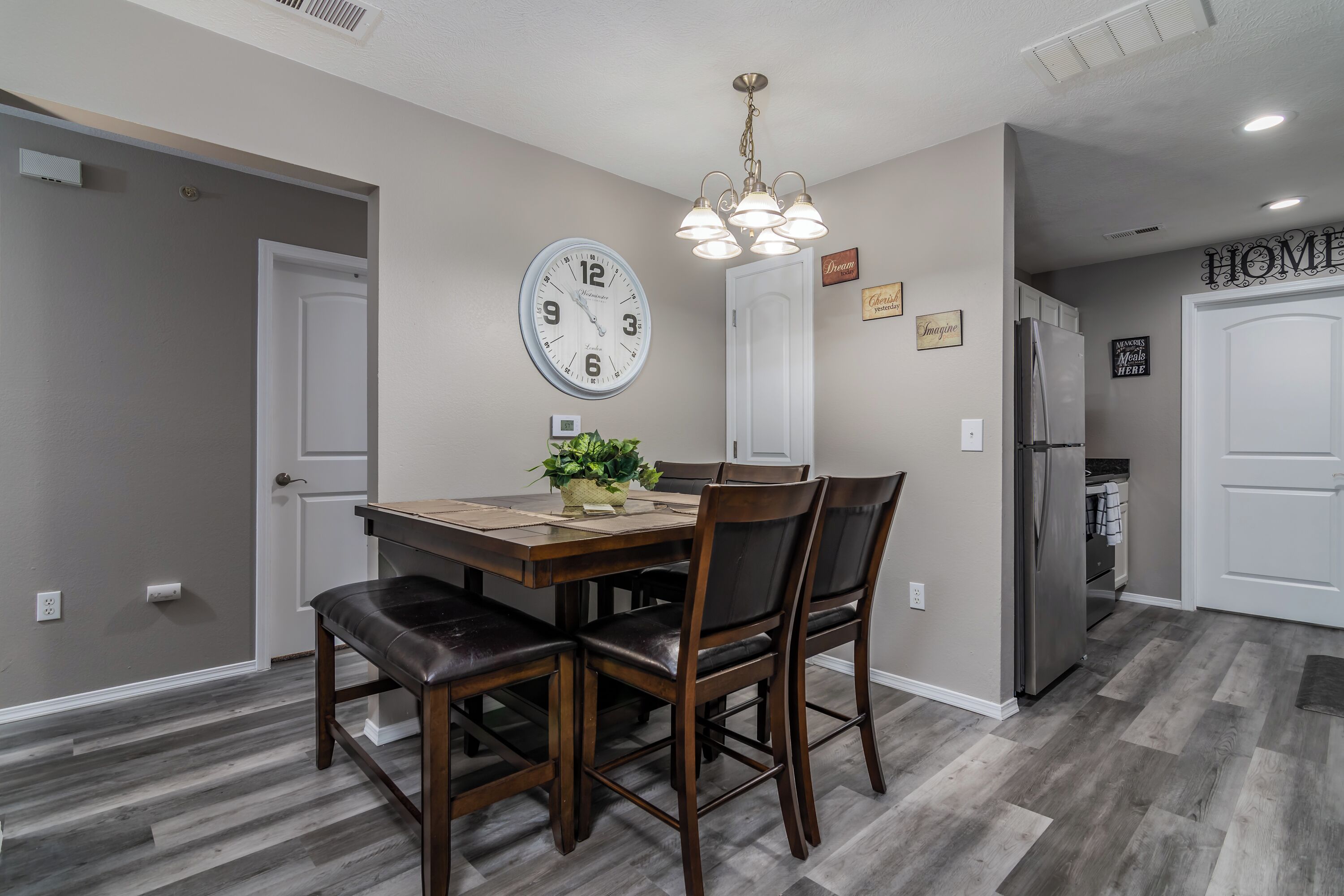 A dining area with a wooden table, chairs, and a clock on the wall.