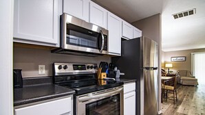 A modern kitchen with stainless steel appliances, white cabinetry, and a dining area with a table and chairs.