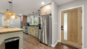 Eine moderne Küche mit einem Edelstahlkühlschrank, Holzschränken und einem eingebauten Geschirrspüler.
