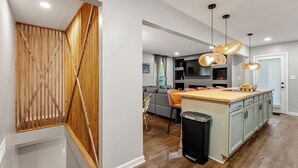 Eine moderne Küche mit Kochinsel, Holztreppe und Pendelleuchten.