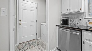 A compact kitchen with white cabinetry, a dishwasher, and a microwave. - The VB Haven (Van Buren)