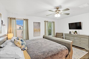 A bedroom with a bed, a ceiling fan, a dresser, a television, and a window with curtains. - Quiet, Cozy, Clean and Safe NW Tucson Home near Omni Resort. (Tucson)