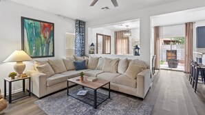Ein modernes Wohnzimmer mit einem beigefarbenen Ecksofa, einem Couchtisch und einem Deckenventilator.