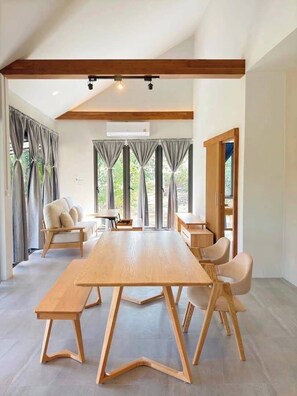 Une pièce spacieuse avec une grande table en bois, deux chaises, un canapé et un meuble en bois.