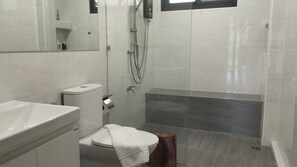 Une salle de bain comprenant des toilettes, un lavabo et un espace douche.