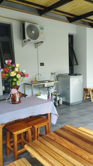 Une cuisine équipée d’un évier, d’un réfrigérateur et d’un ventilateur fixé au mur.