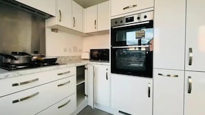 A modern kitchen with white cabinets, a stove, and an oven.