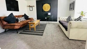 A modern living room with a brown leather sofa, a white sofa, a coffee table, and a large round artwork on the wall.