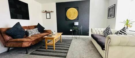 A modern living room with a brown leather sofa, a white sofa, a coffee table, and a large round artwork on the wall.
