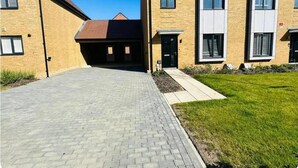 A modern building with a paved driveway leading to a gated entrance, surrounded by well-maintained grass and a clear blue sky.