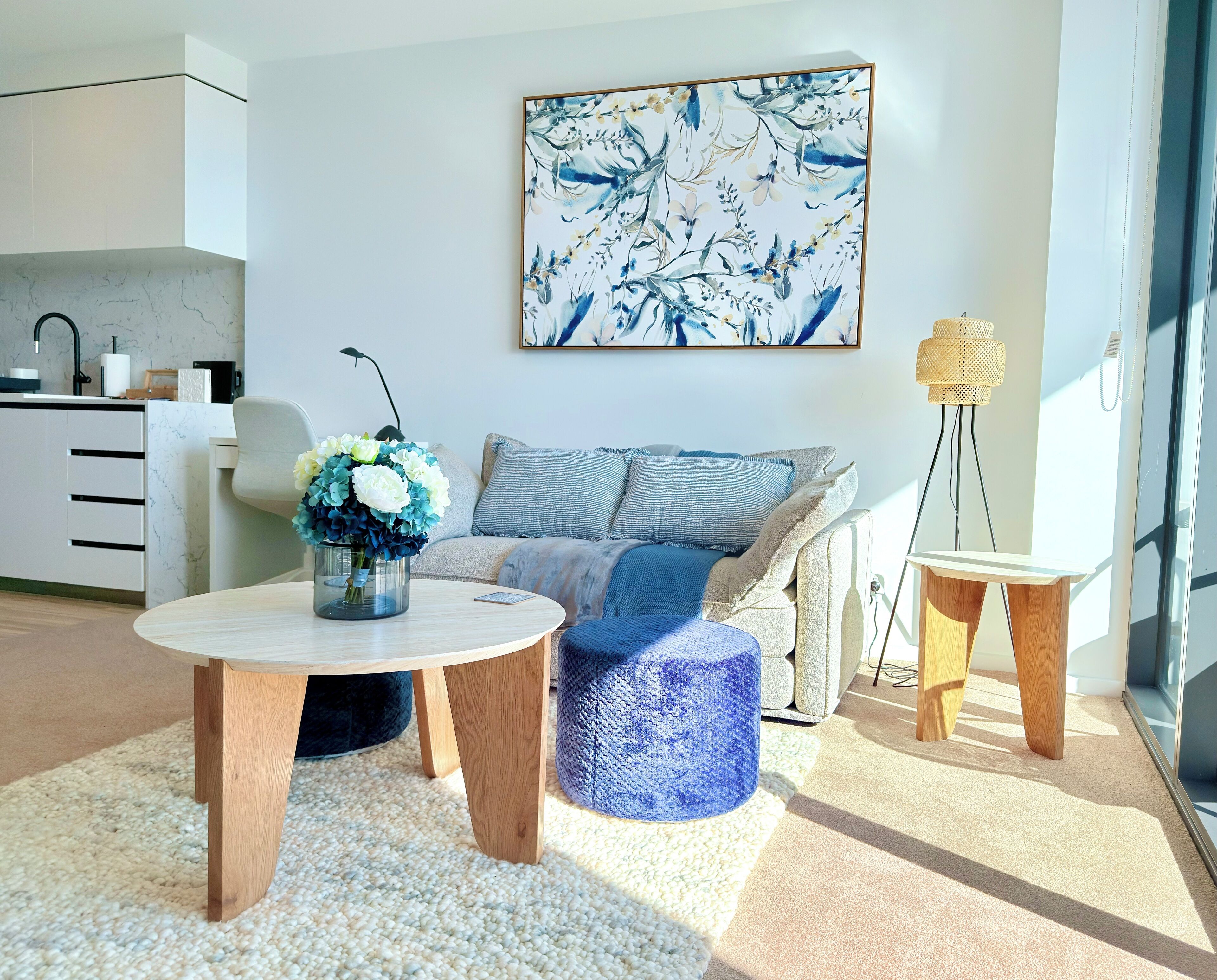 Un salon moderne avec un canapé, une table basse et une table d’appoint. Un tableau est accroché au mur et une lampe est posée sur la table d’appoint.