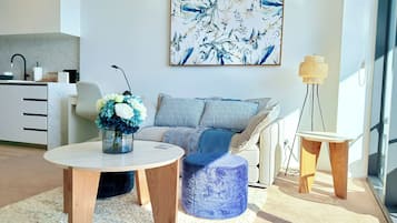 Un salon moderne avec un canapé, une table basse et une table d’appoint. Un tableau est accroché au mur et une lampe est posée sur la table d’appoint.