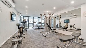 A modern gym with cardio machines, weightlifting equipment, and a large mirror.