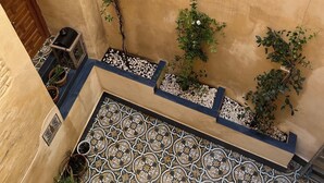 A courtyard with a tiled floor, potted plants, and a wooden door.