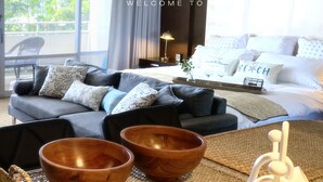 A modern hotel room with a large window, a sofa, a coffee table, and a tray with bowls and a vase. - Ocean View Waikiki Luxury Ilikai Hotel~ (Honolulu)
