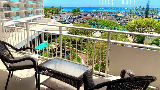 A balcony with wicker furniture overlooking a hotel and a view of the beach and marina. - Ocean View Waikiki Luxury Ilikai Hotel~ (Honolulu)