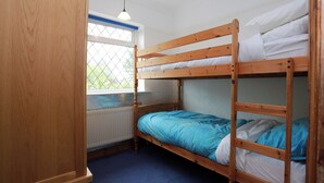Dormitorio con literas, ventana, paredes de madera y radiador.