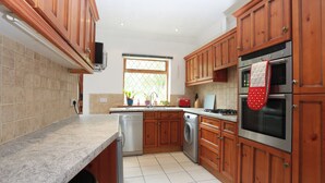 Una cocina con armarios de madera, lavavajillas, lavadora, estufa y microondas.