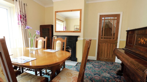Un comedor con una mesa de madera, sillas, una chimenea y un espejo en la pared.
