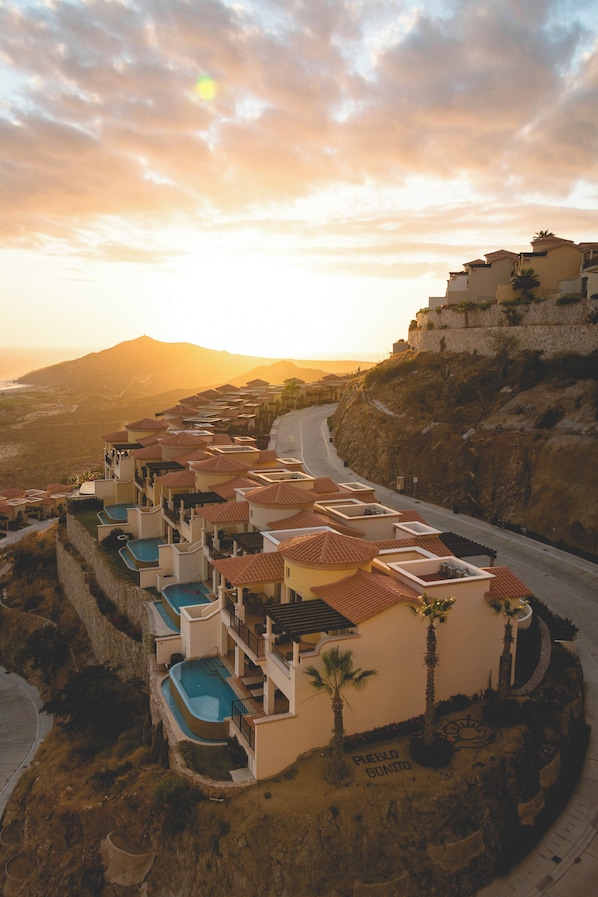 A resort with multiple buildings, swimming pools, and a curved road.