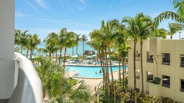 A pool area with palm trees and a view of the ocean.