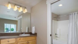 Une salle de bain avec un meuble-lavabo en bois, un grand miroir et un espace douche.